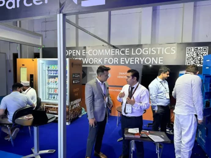 Team talking with visitors at the Kineto booth beside a vending machine at Seamless Middle East